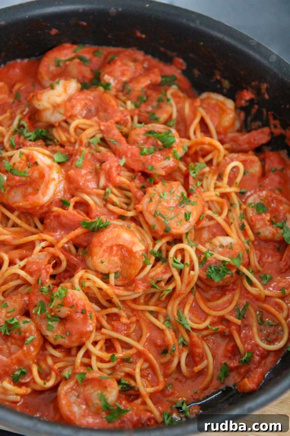 creamy spicy shrimp spaghetti with parsley in a black skillet 