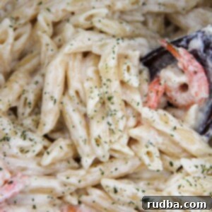 Creamy Instant Pot Shrimp Alfredo 5 Shrimp and pasta covered in sauce with parsley and a wooden spoon up close.