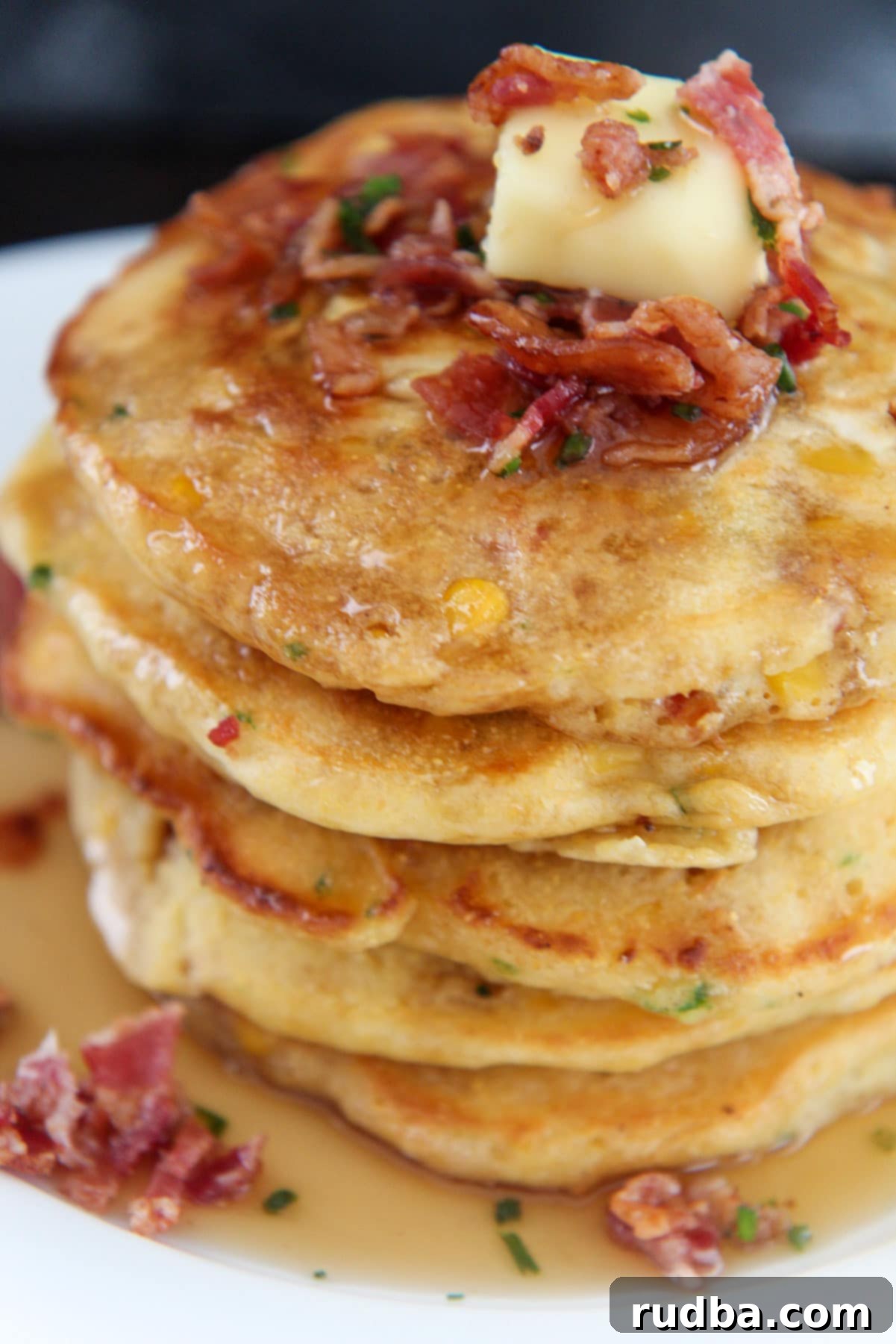 pancakes with a slice of butter and crispy bacon on top up close. 