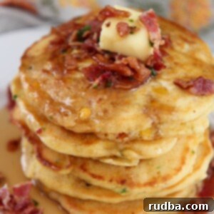 Savory Bacon Corn Pancakes 5 a short stack of bacon and corn pancakes on a white plate with syrup on top.