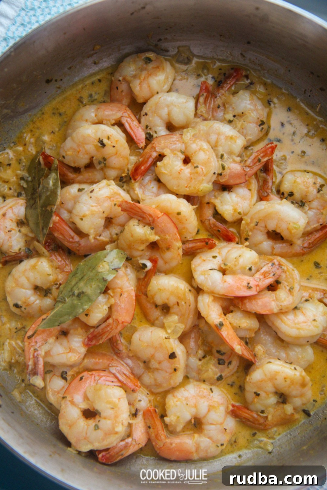 A close-up shot of creamy New Orleans style shrimp simmering in a skillet, garnished with fresh herbs.