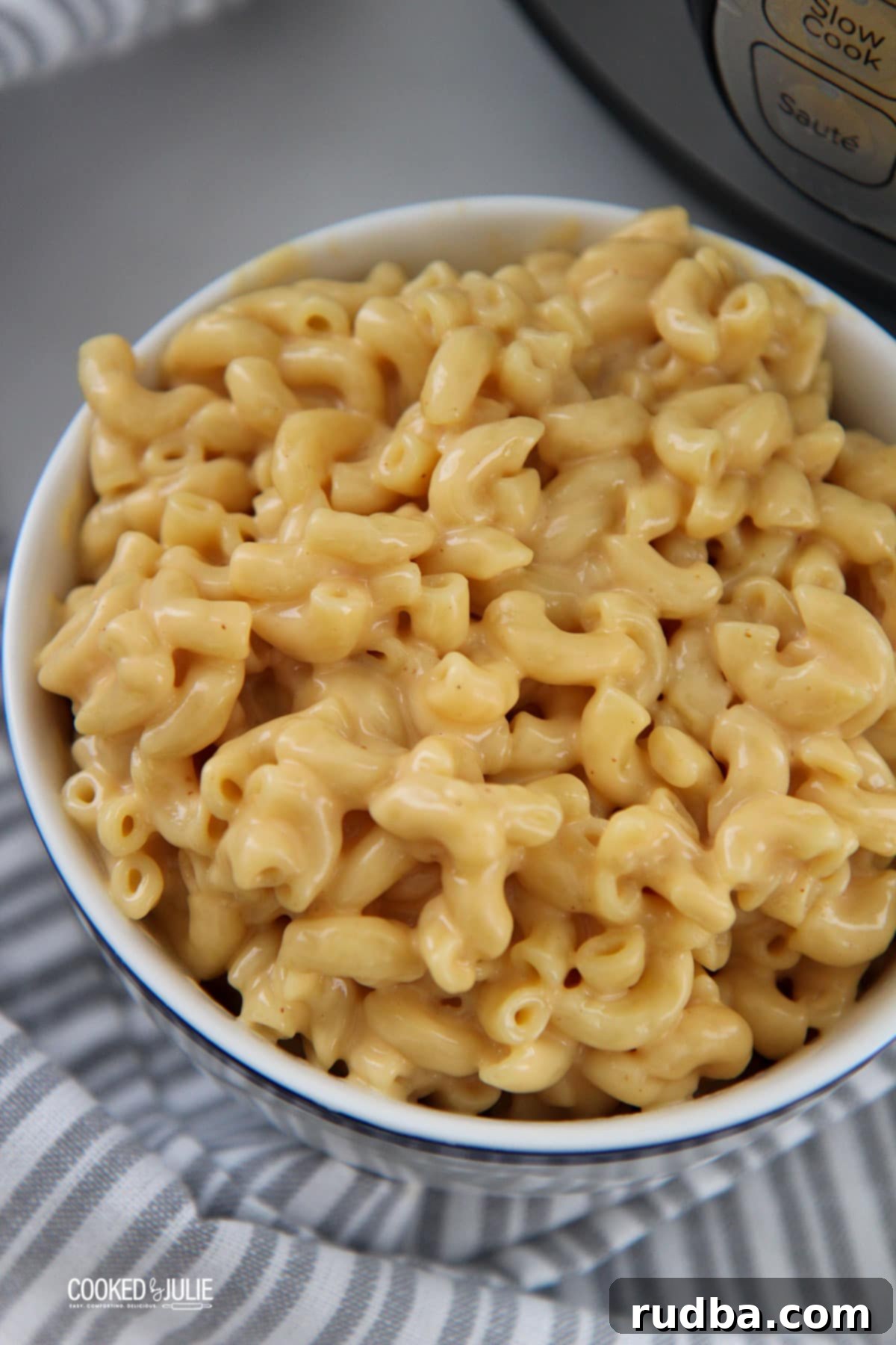 mac and cheese in a white bowl with a gray and white towel on the side. 