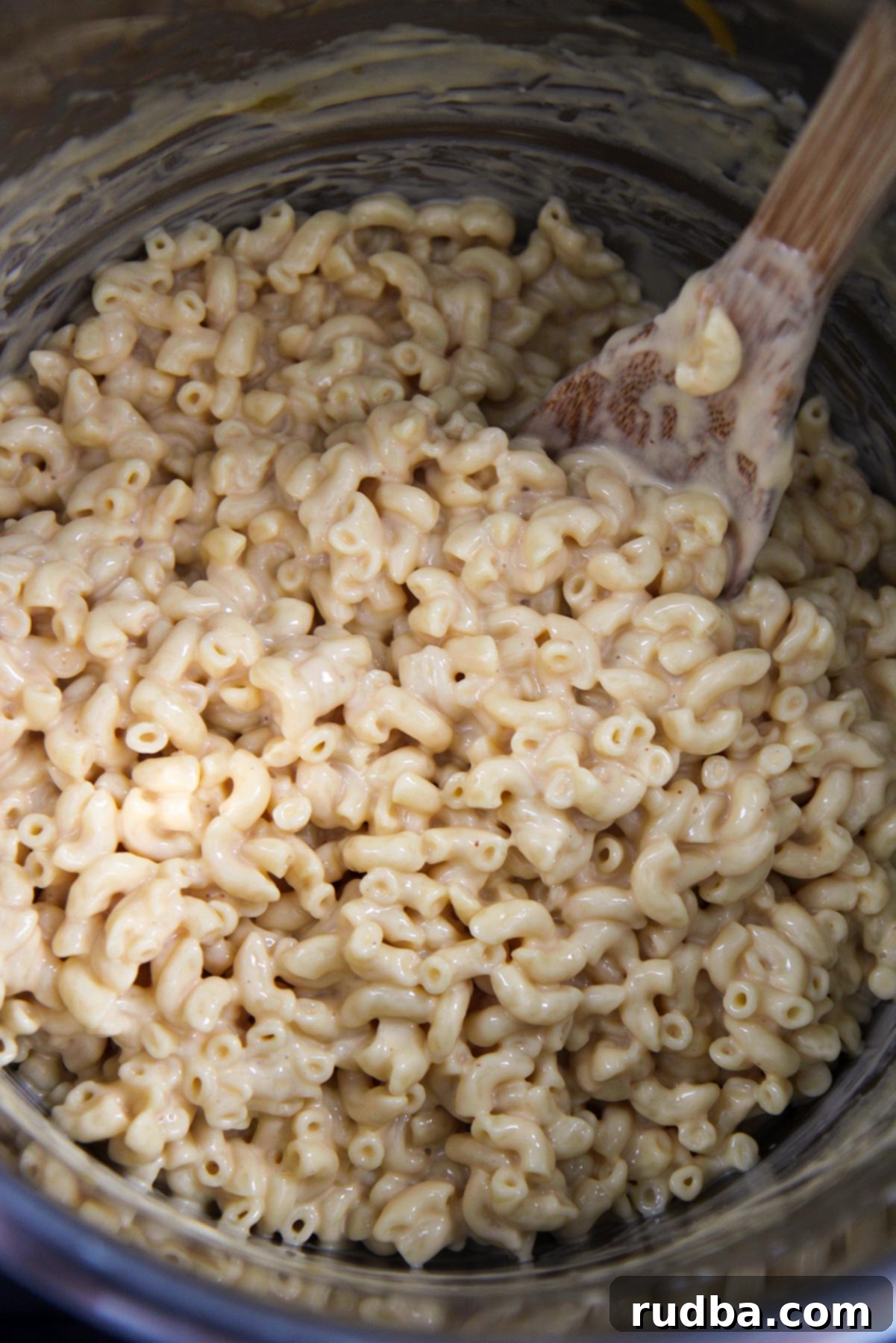 elbow macaroni and a wooden spoon inside a pressure cooker 