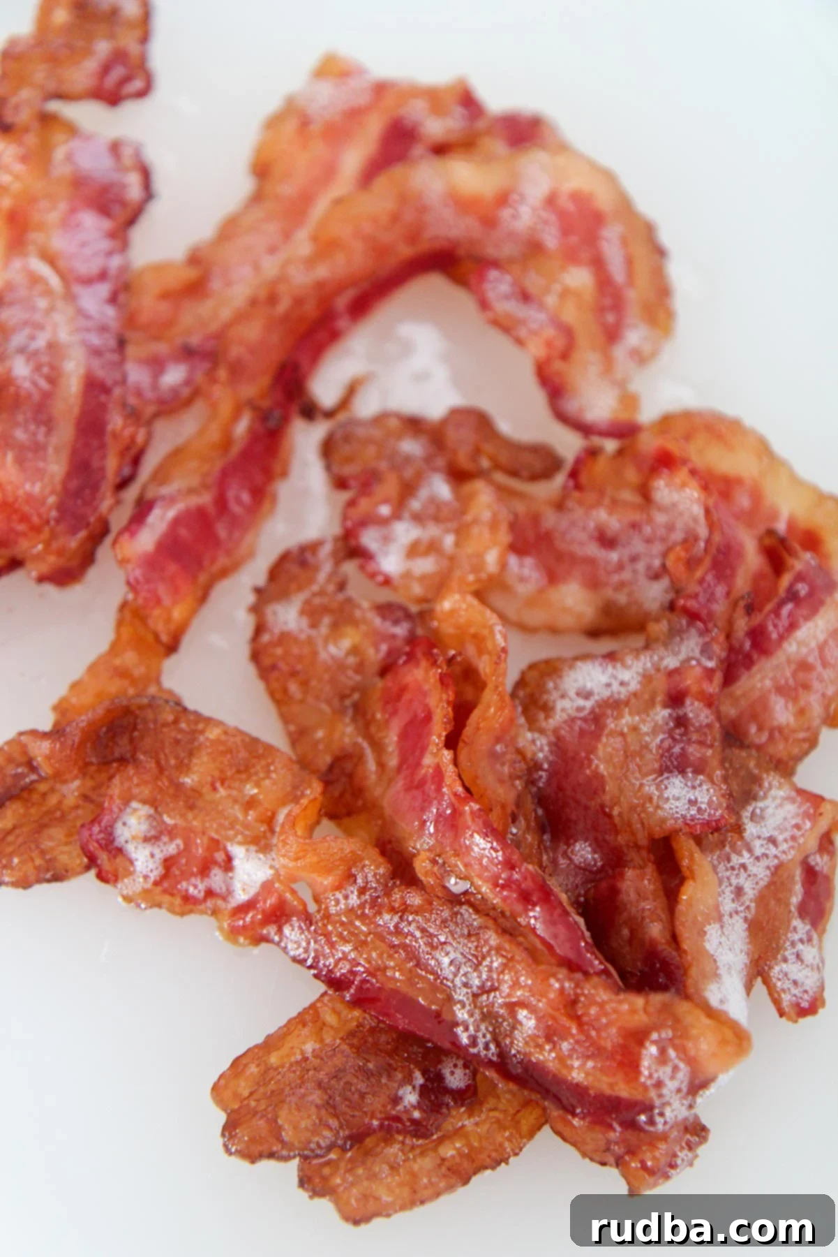 one pound of crispy bacon up close on a white chopping board.