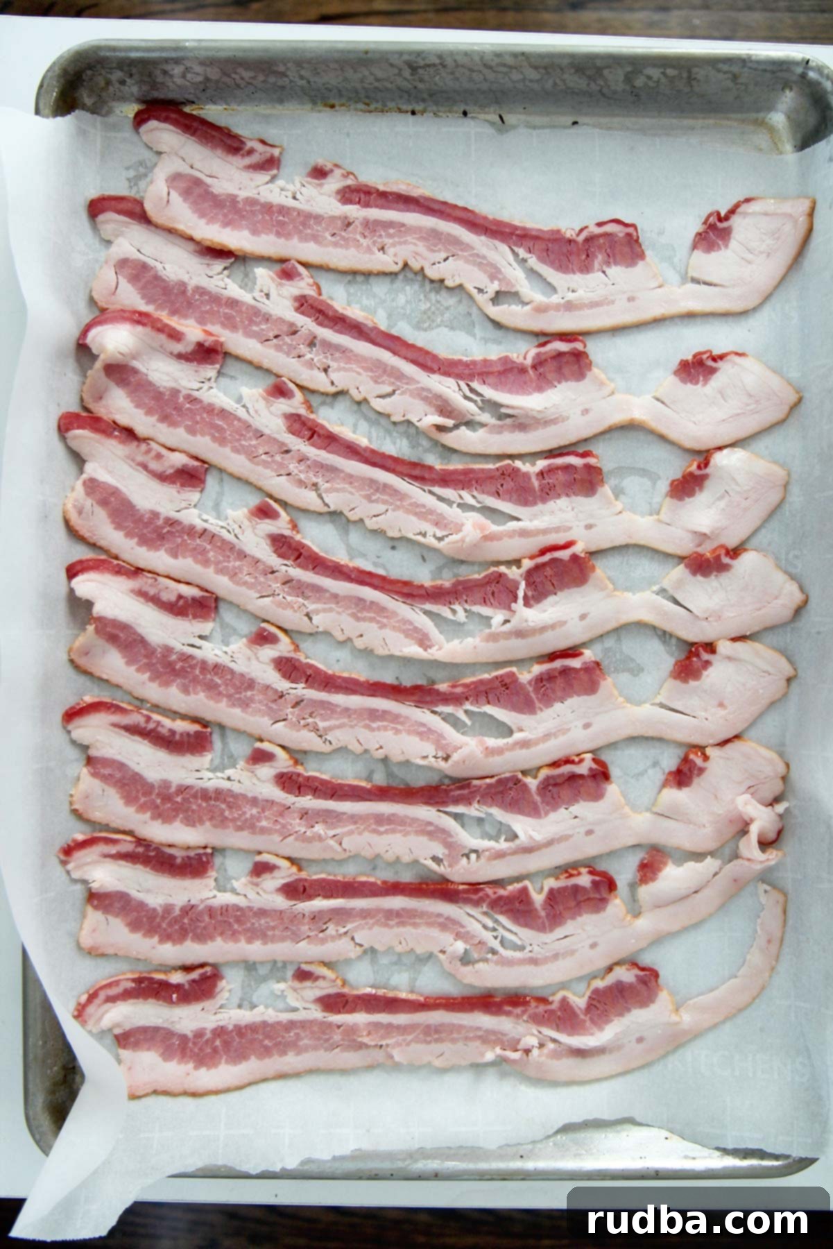 eight slices of raw bacon on a baking sheet lines with parchment paper. 