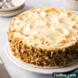 A close-up of a slice of carrot cake, showing the moist layers and rich cream cheese frosting.