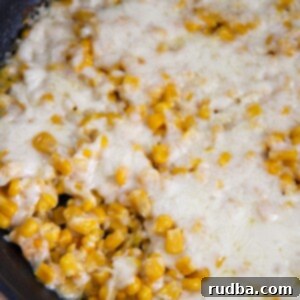 Creamy Cheesy Corn 5 corn and cheese in a black skillet.
