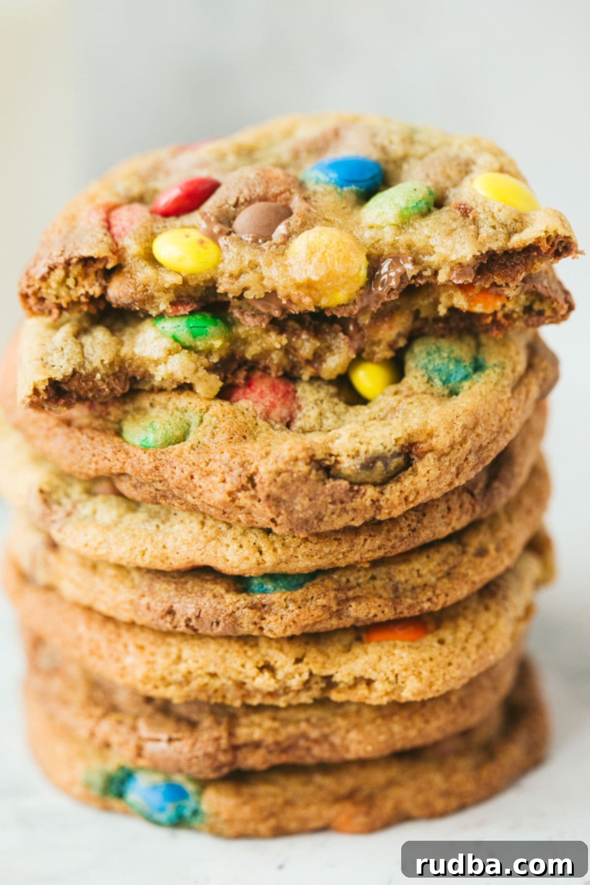 eight m&m cookies stacked on top of each other. One cookie is cut in half. 