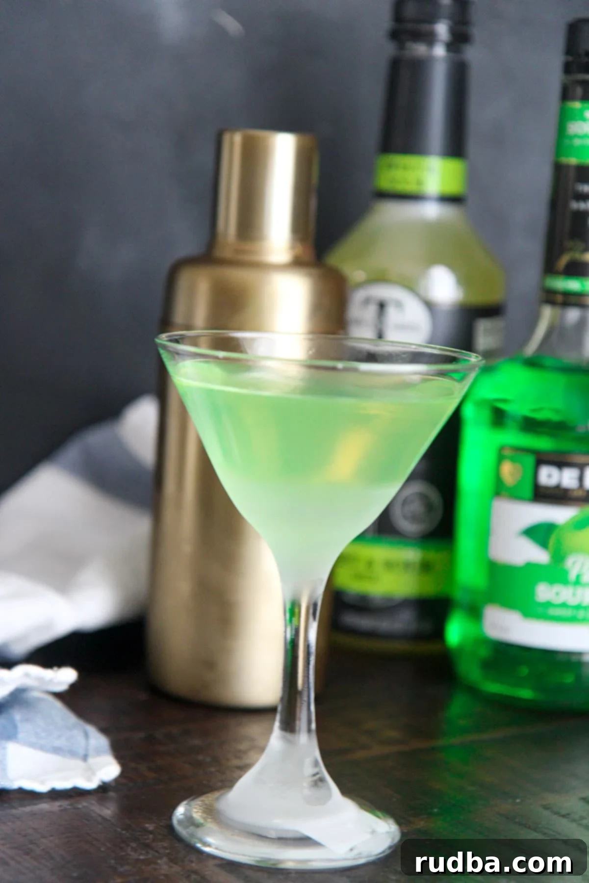 green appletini with a shaker and apple pucker alcohol in the background