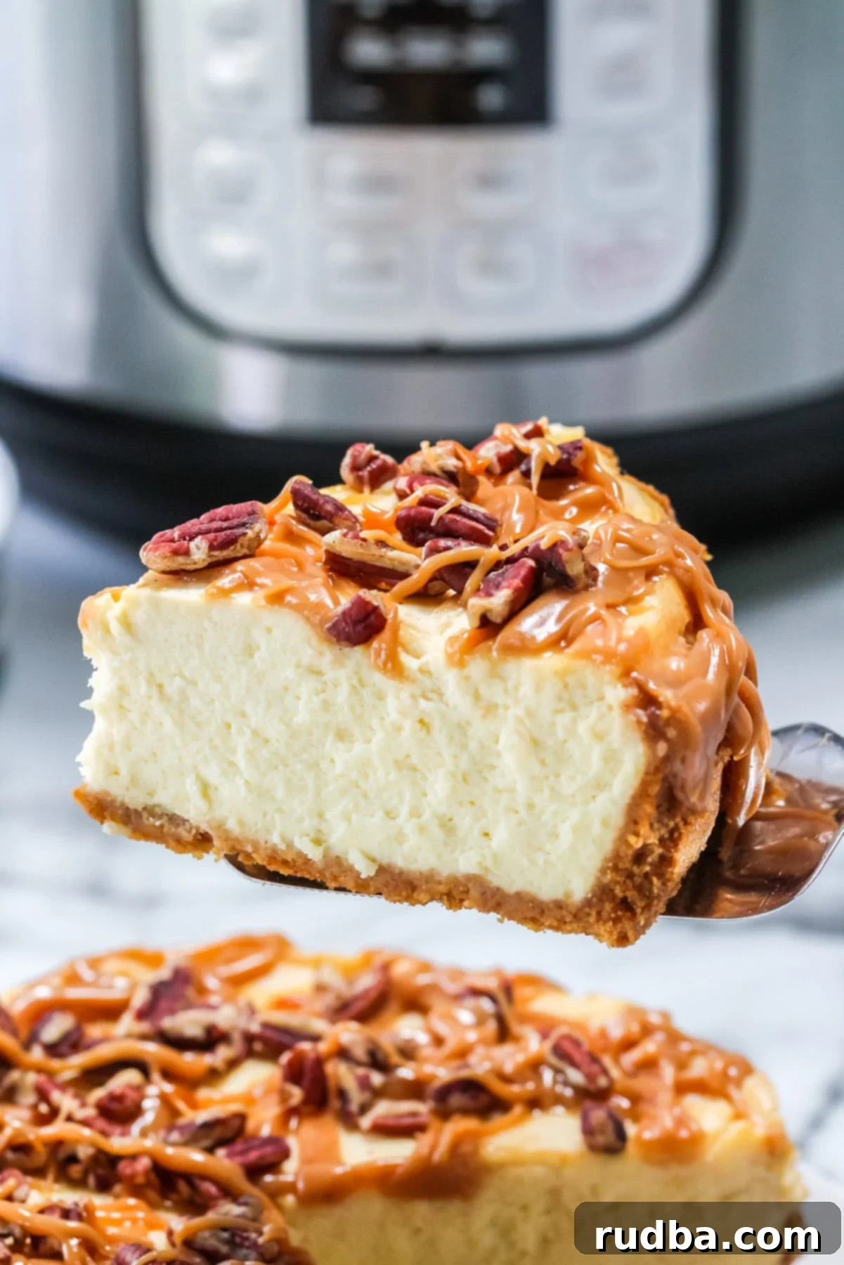 A close-up of a perfect slice of Instant Pot Salted Caramel Cheesecake, showing the creamy texture, graham cracker crust, and generous drizzle of glistening caramel sauce with a few pecans.