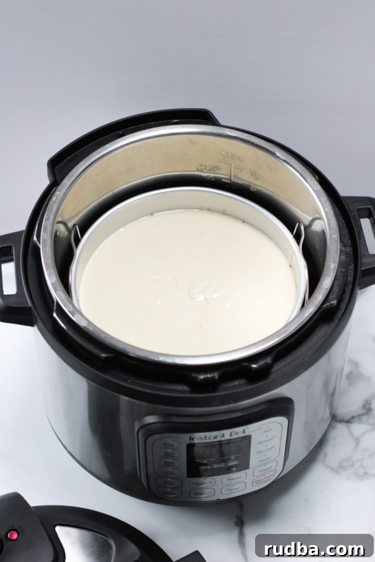 A springform pan containing cheesecake batter, positioned inside an Instant Pot on a trivet, ready for pressure cooking.