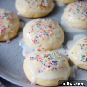 Seven Italian lemon ricotta cookies with a glaze and sprinkles on a gray plate.