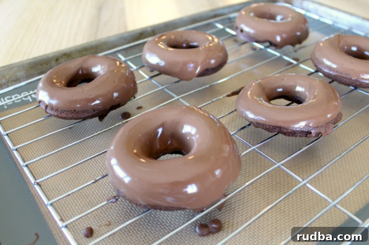 six glazed chocolate donuts on a wire rack 