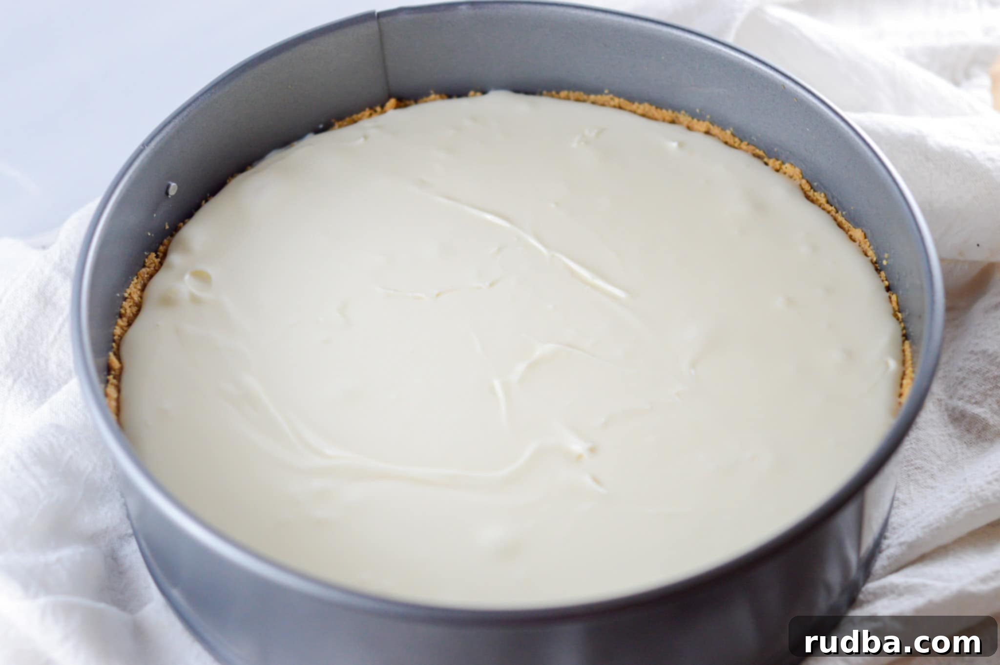 Creamy no-bake cheesecake filling poured into a graham cracker crust in a springform pan, ready for chilling.