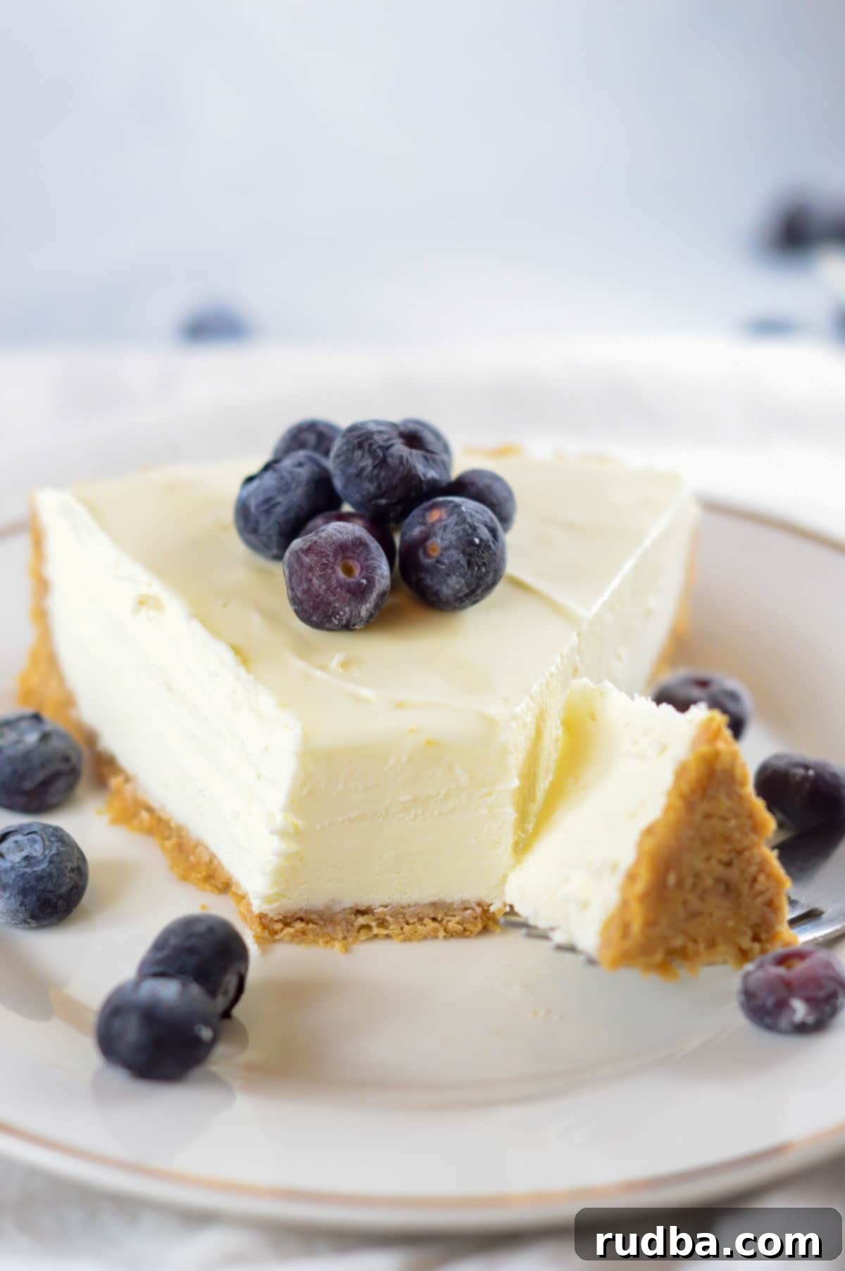 A fork slicing into a creamy slice of no-bake cheesecake, highlighting its smooth texture.
