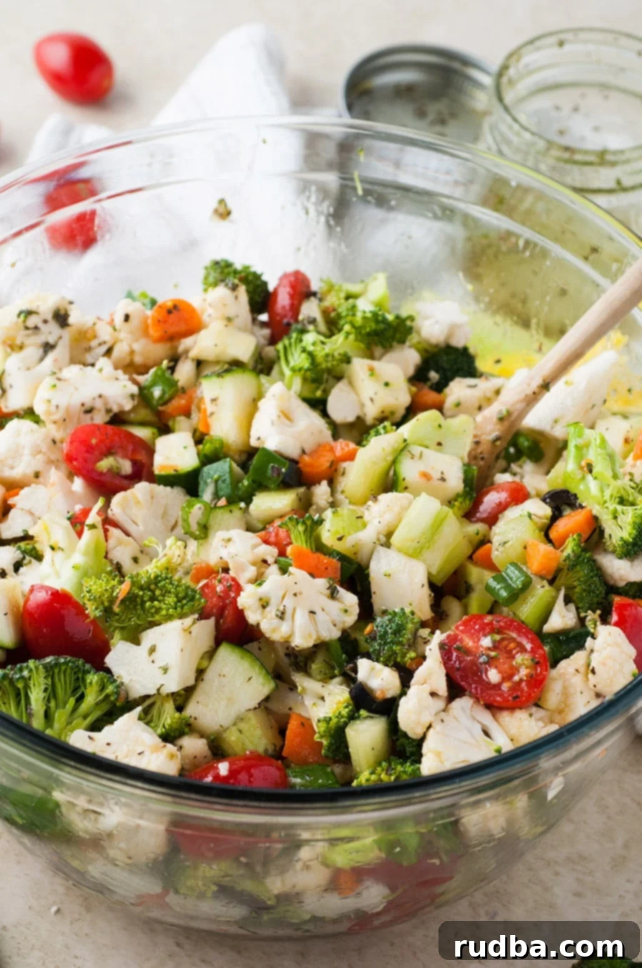 a bowl with colorful raw vegetables with a wooden spoon.