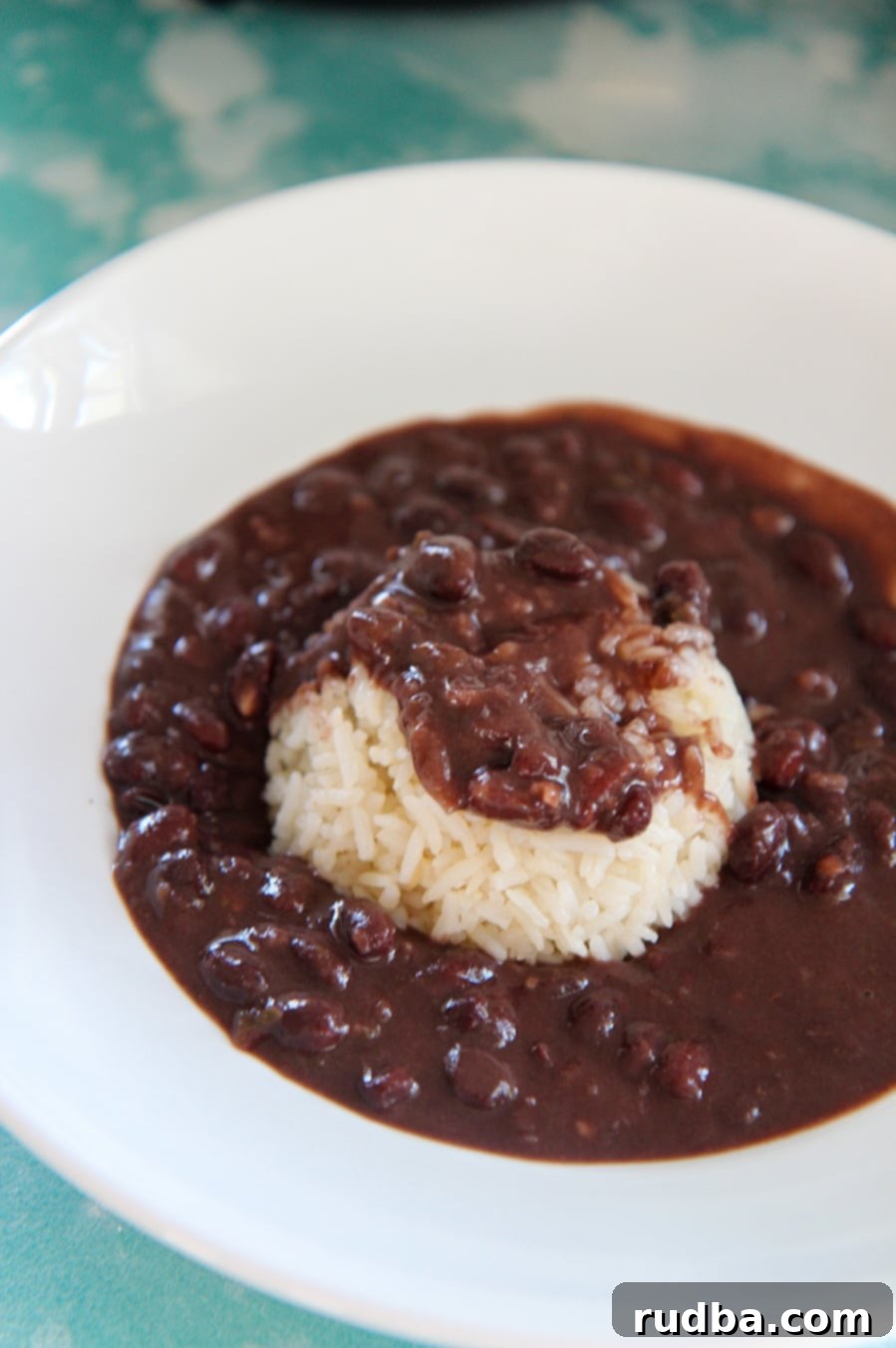 black beans and white rice in a white bowl on top of a blue surface. 