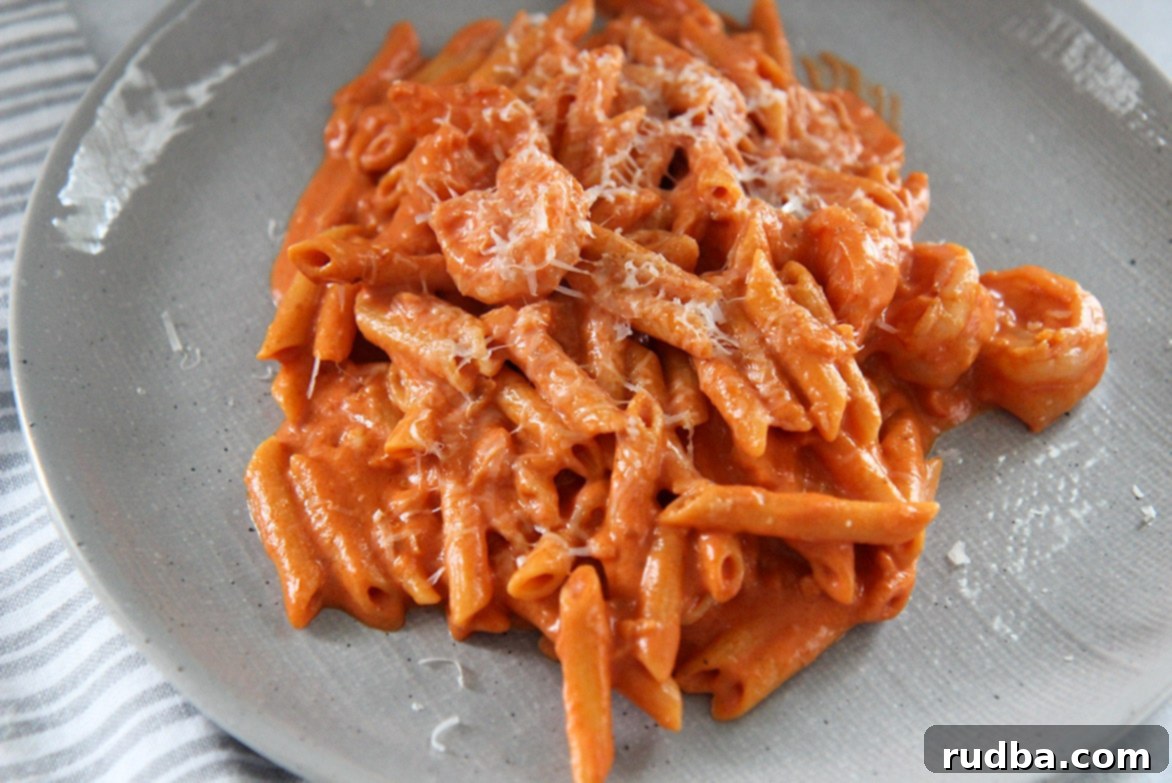 pasta, shrimp, sauce, and parmesan cheese on a gray plate up close. 