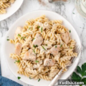 Aromatic Chicken Thyme Pasta 5 chicken and pasta in a white bowl with a fork and a blue towel on the side.