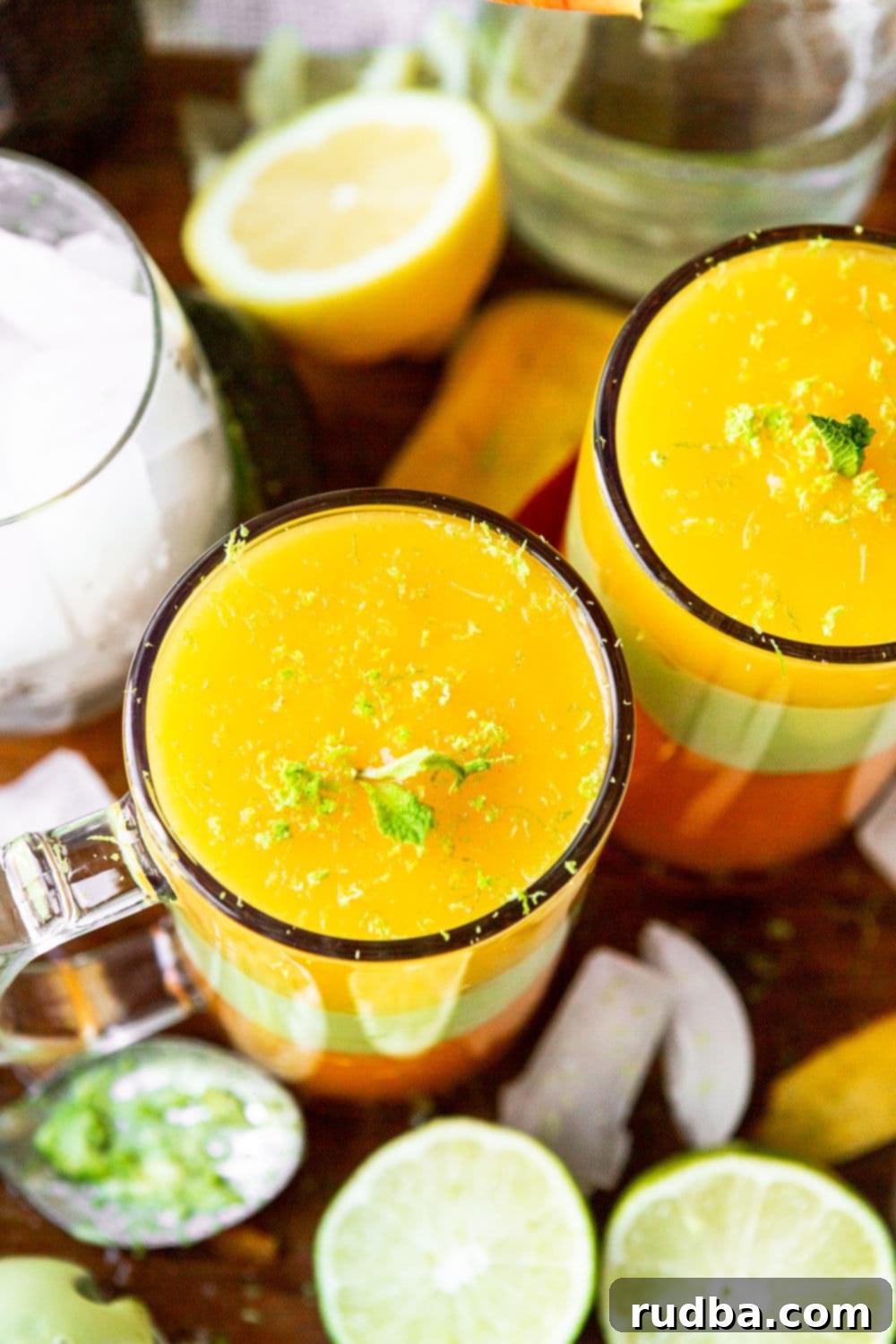 two tall glasses with yellow and green juice on a wooden board.