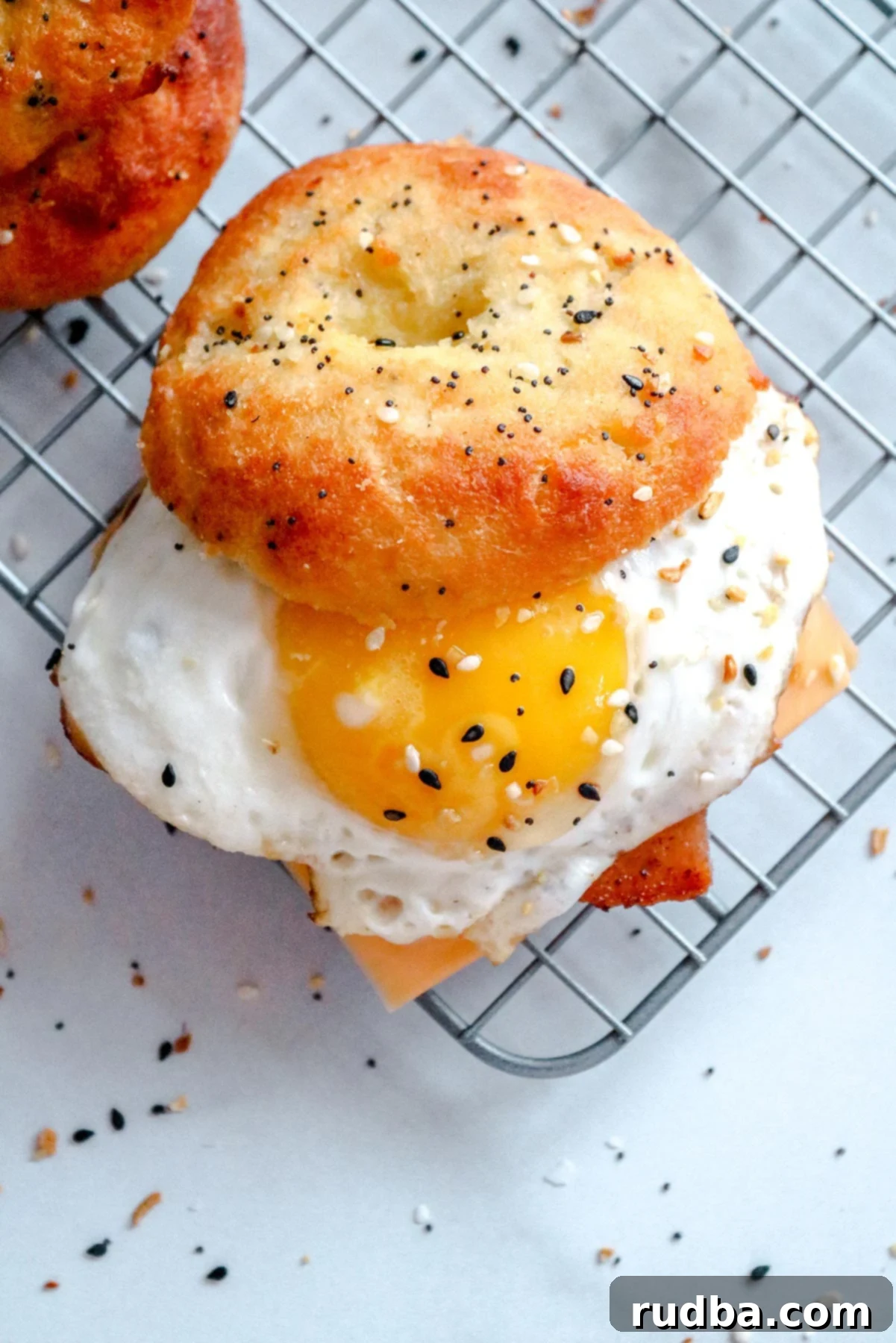 A keto breakfast sandwich with a sunny side up egg, everything bagel, and cheese on a wire rack.