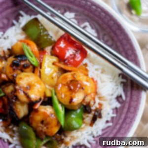 Sticky Honey-Citrus Shrimp 4 sweet and sour shrimp over white rice in a purple bowl with chop sticks on top.
