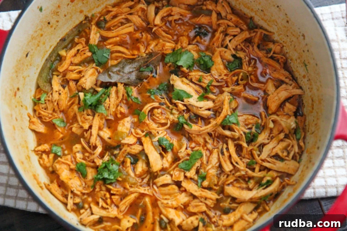 shredded chicken in sauce inside of a dutch oven. 