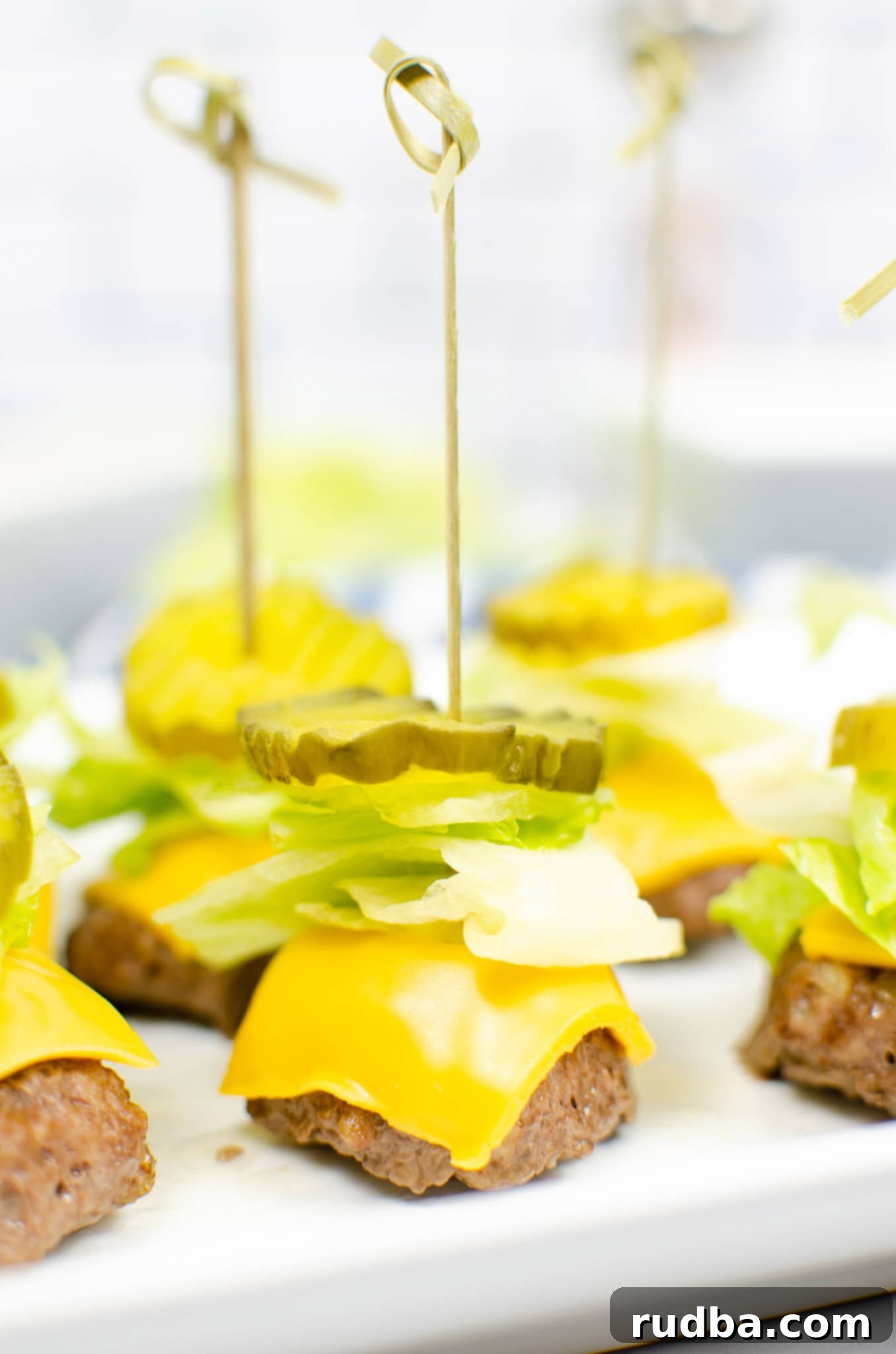 Close-up of a Big Mac Bite with melted cheese, special sauce, shredded lettuce, and a pickle slice, held by a toothpick.