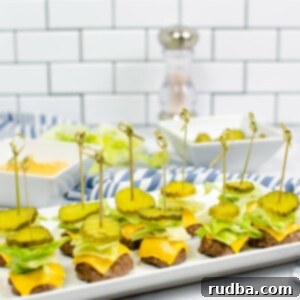 Big Mac Poppers 4 ten big mac bites with lettuce, cheese, and pickles on top of a white plate with sauce, pickles, and pepper in the background.