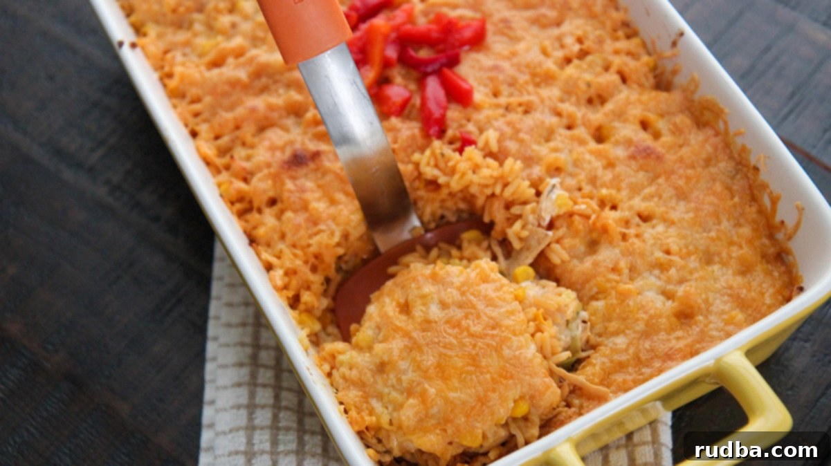 A casserole dish filled with golden Arroz Imperial, with an orange spatula lifting a generous portion, showcasing the creamy layers.