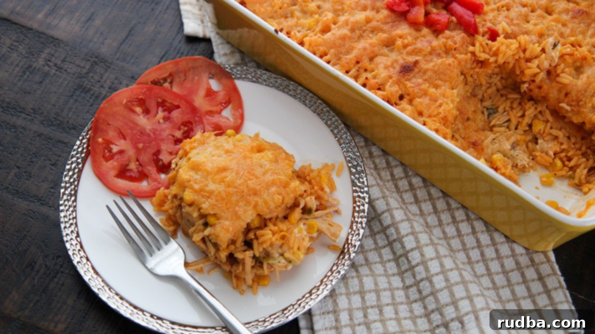 A plated serving of Arroz Imperial, showing the layers of yellow rice, shredded chicken, and melted cheese, garnished with fresh tomato slices and a fork, with the casserole dish blurred in the background.