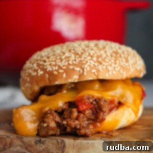 Homestyle Sloppy Joes 4 sloppy joe sandwich with cheese up close and a red dutch oven in the background.