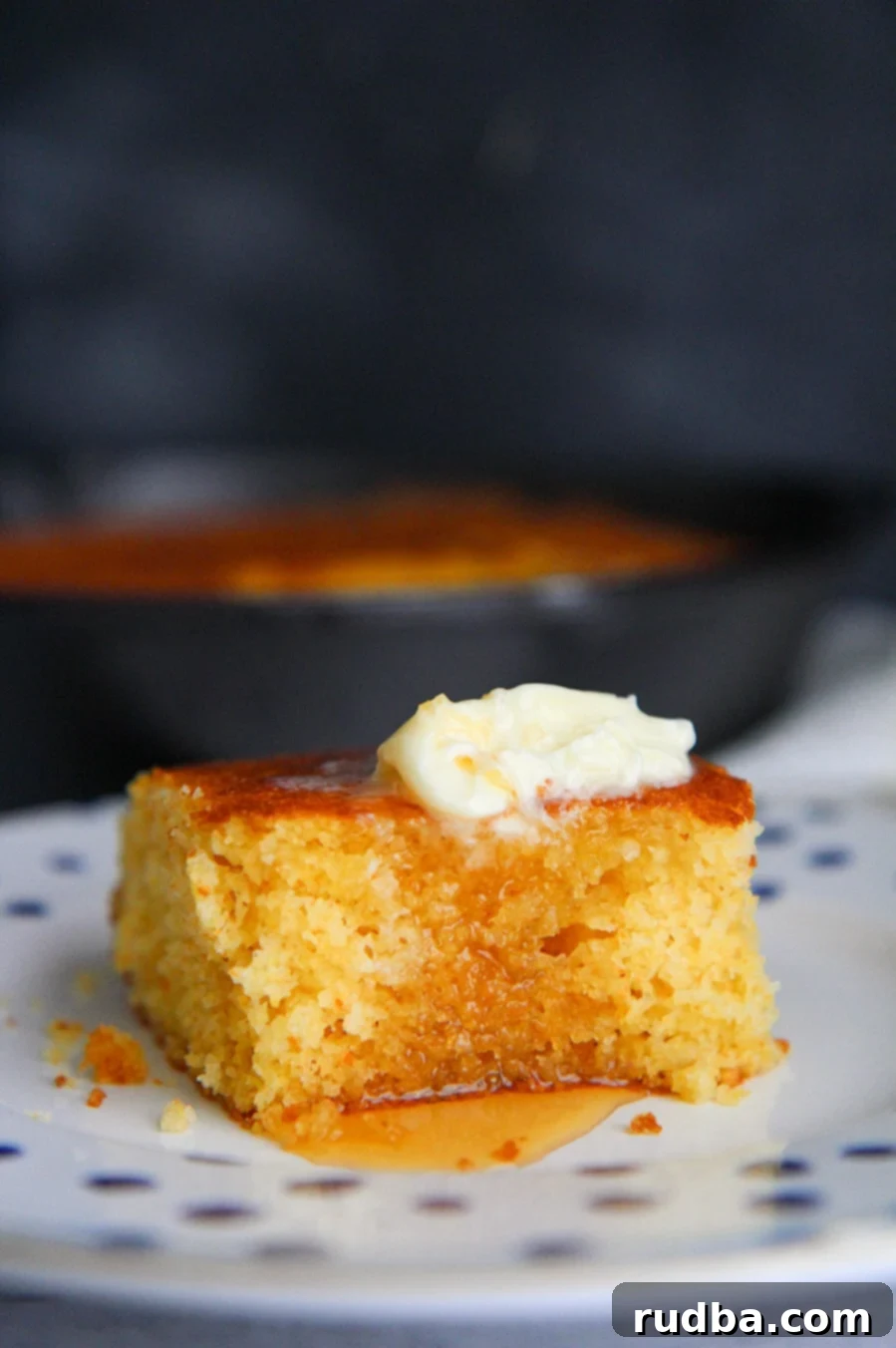 a slice of cornbread with butter and honey on a plate. 