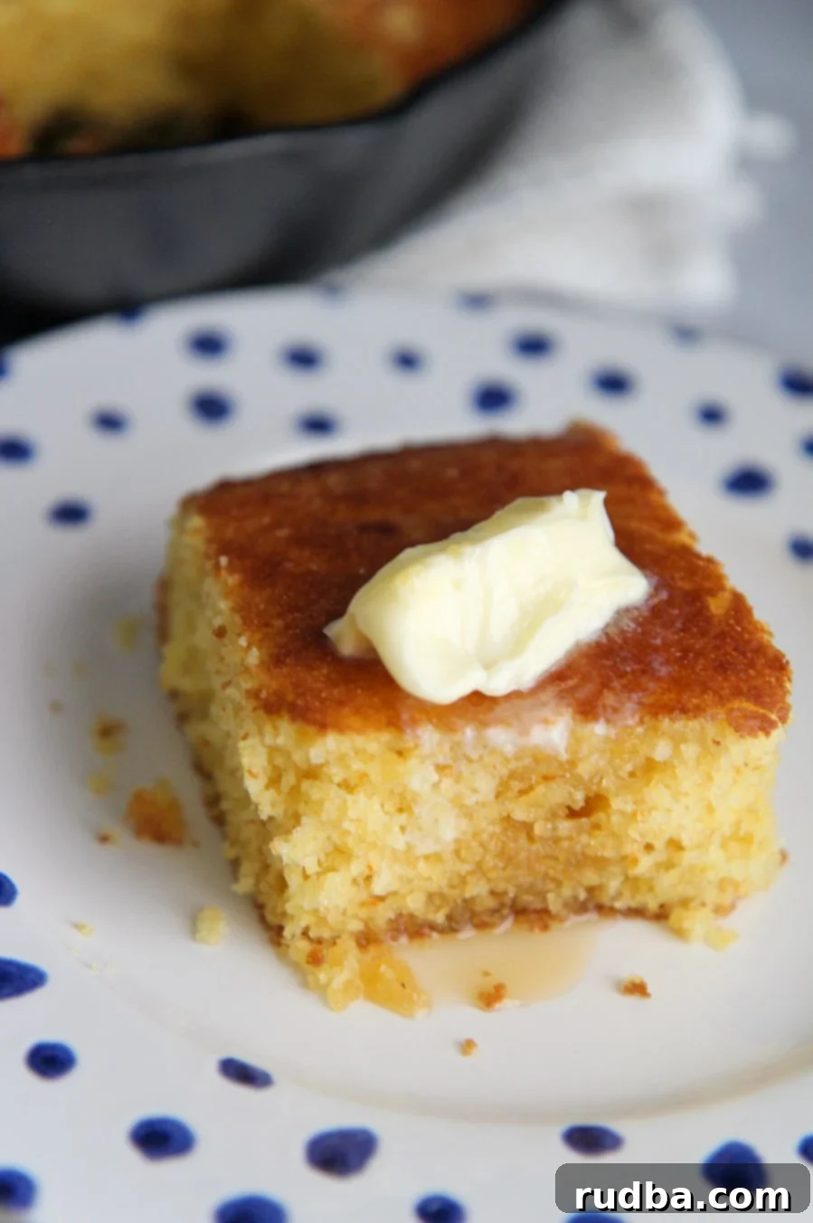 a slice of cornbread on a white plate with blue dots. 