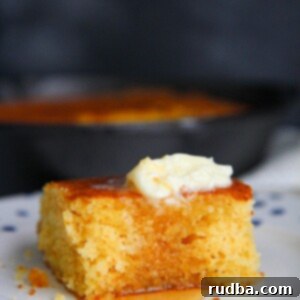 Golden Buttermilk Cornbread Delight 5 a slice of cornbread with butter and honey on a plate.