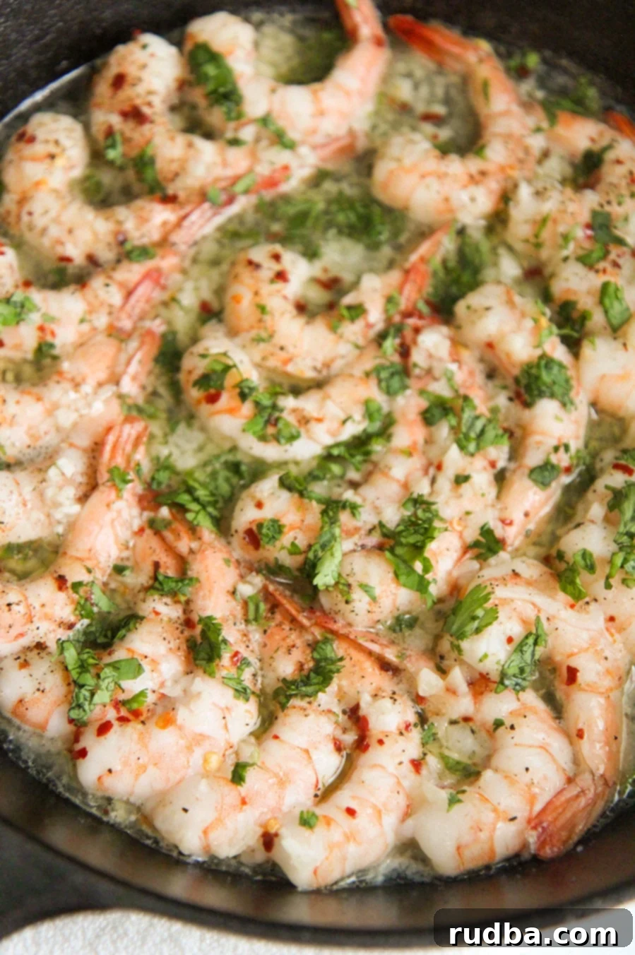 baked shrimp with parsley in a cast iron skillet up close.