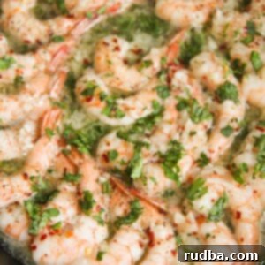 baked shrimp with parsley in a cast iron skillet up close.