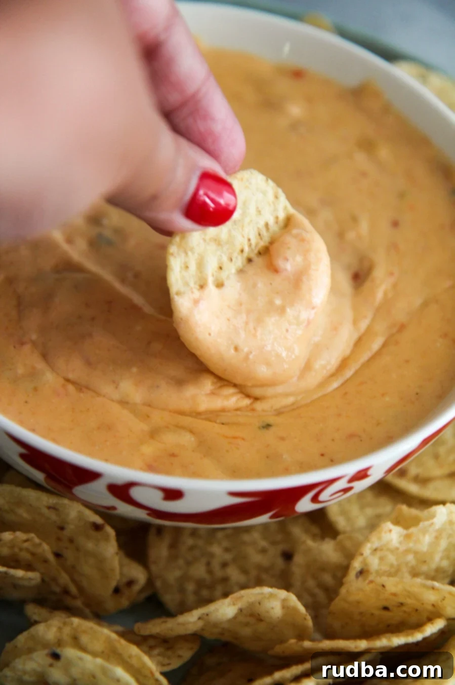 a chip dipped in a bowl of yellow queso.