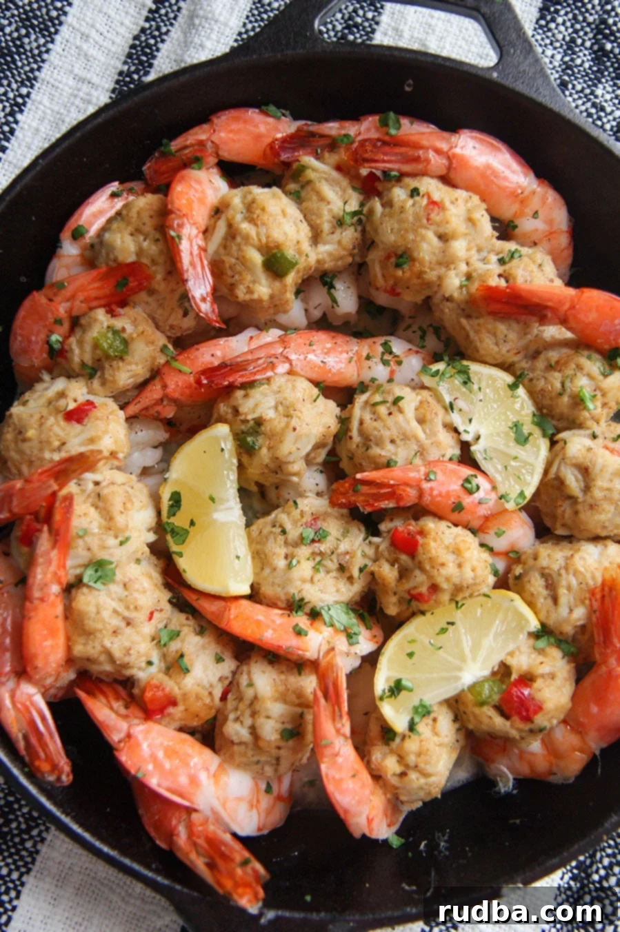 Delicious crab stuffed shrimp in a cast iron skillet with lemon wedges and fresh parsley garnish, ready to serve.