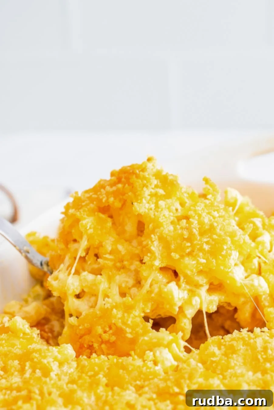 A close-up shot of a spoonful of baked mac and cheese, showing its golden-brown topping and gooey texture.