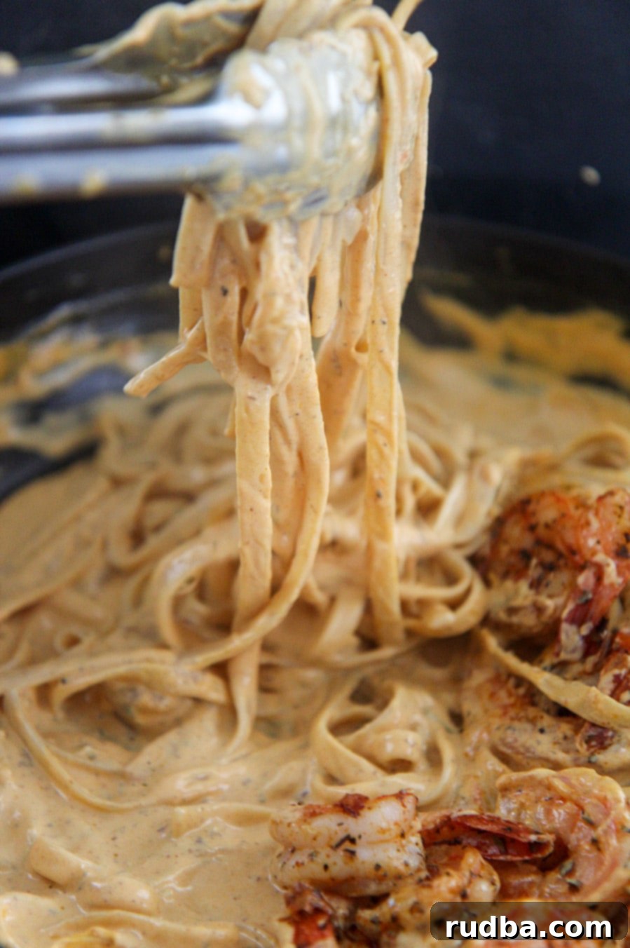 tongs holding a serving of pumpkin fettuccine alfredo