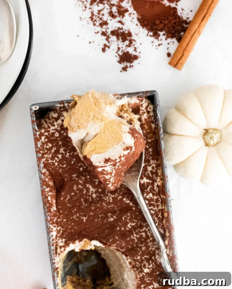 pumpkin tiramisu in a loaf pan with a spoon and a white pumpkin on the side.