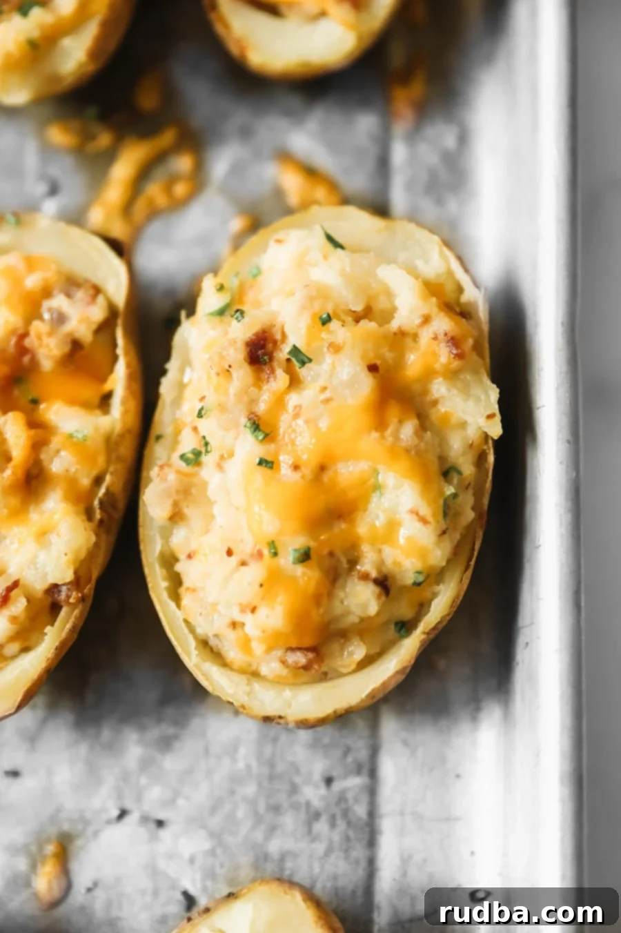 twice baked potato with melted yellow cheese and green herbs on top. 