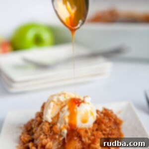 Warm Spiced Apple Delight 5 A spoon drizzling caramel sauce over apple crisp with vanilla ice cream on a white plate, showcasing the dessert's deliciousness.