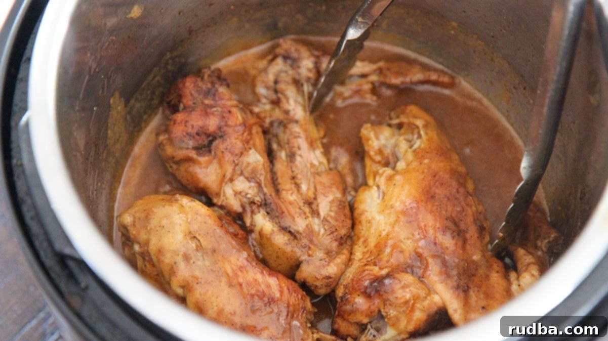 three smothered turkey wings in the instant pot with a pair of tongs.