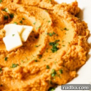 Velvety Sweet Potato Mash 4 Mashed sweet potatoes with butter and fresh green herbs on top in a small round bowl.