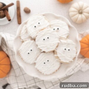 Bandaged Bites 5 mummy cookies on a white plate with pumpkins on the side.