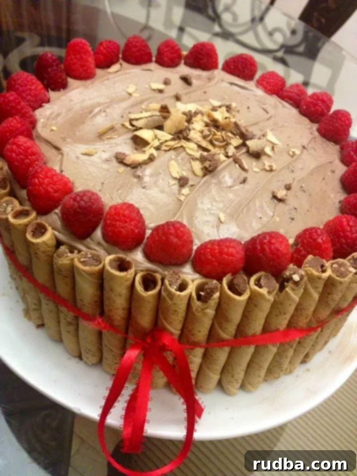 This Nutella cake is made with a Nutella frosting and topped with raspberries and almond slices, making it a perfect dessert.
