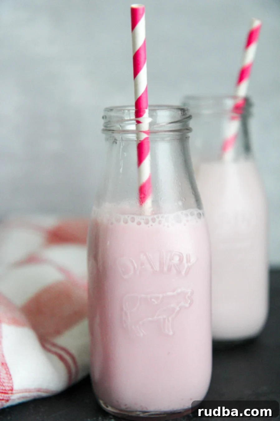 two milk jugs filled with strawberry milk and pink and white straws.