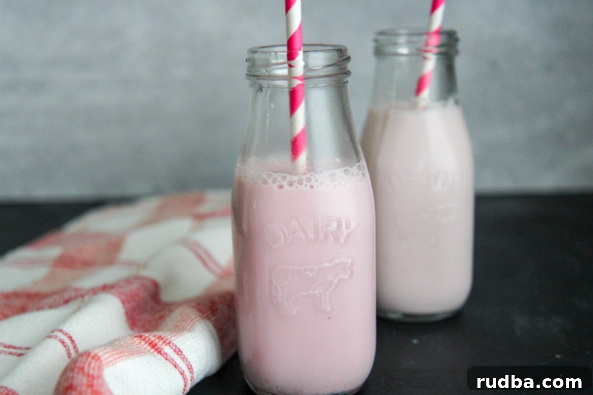 two milk jugs with strawberry milk, straws, and a red and white towel on the side.